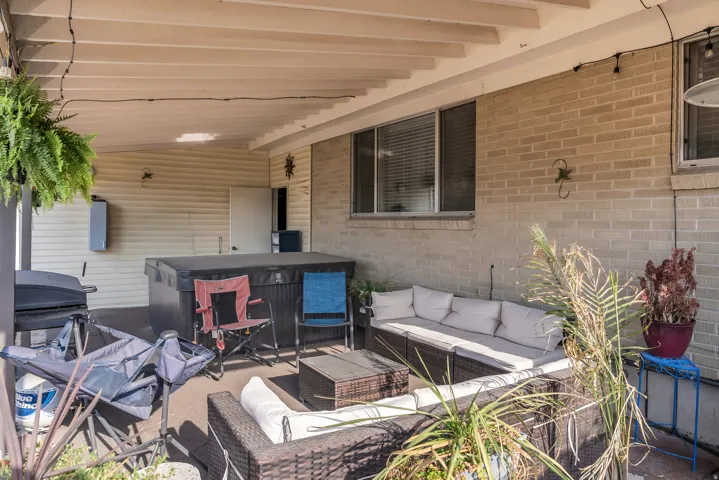 Covered patio featuring a hot tub, brick exterior, and vinyl siding