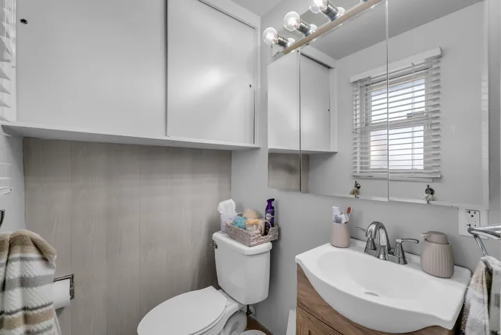 White vanity with integrated sink, chrome faucet, and wood-finish cabinetry