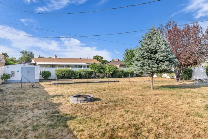 Expansive backyard with a stone fire pit, mature trees, and a utility shed