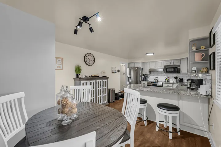 Open-concept kitchen and dining area featuring white cabinetry, stainless steel appliances, quartz countertops, and a center island