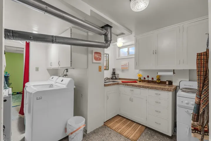 Laundry area featuring a utility sink, white cabinetry, a window, and a ceiling-mounted light fixture