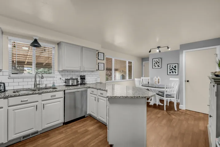 Kitchen featuring light gray cabinetry, granite-style countertops, stainless steel appliances, and wood-finish flooring