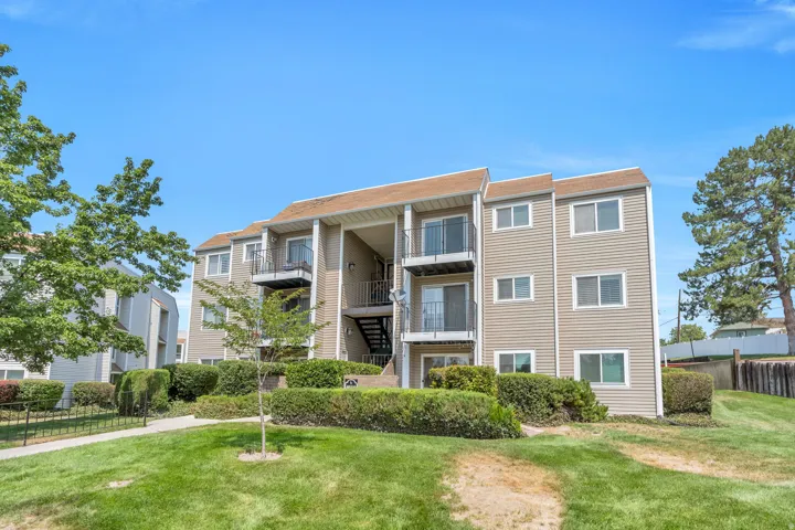 Multi-story building with tan siding, multiple private balconies, and exterior stair access