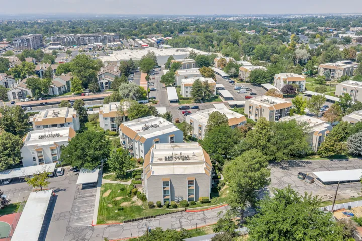 Expansive community with multiple residential buildings, numerous covered parking structures, mature trees, and paved access roads