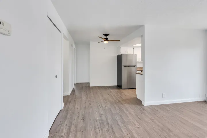 Wood-finish flooring throughout, bright white walls, and a ceiling fan with integrated lighting