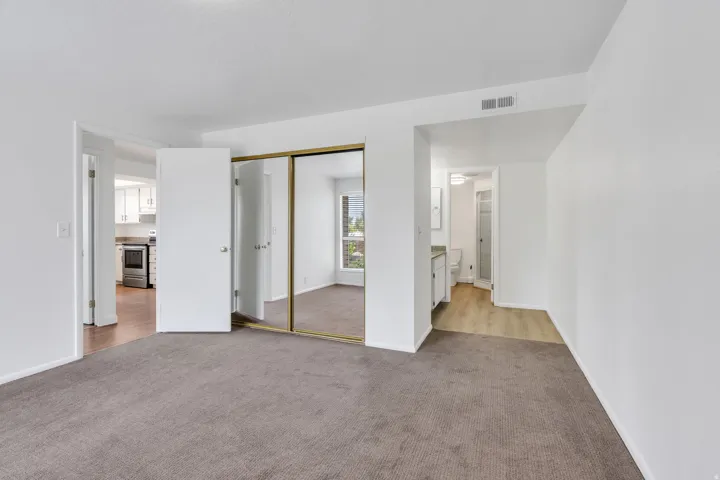 Carpeted flooring, mirrored sliding closet doors, and white walls