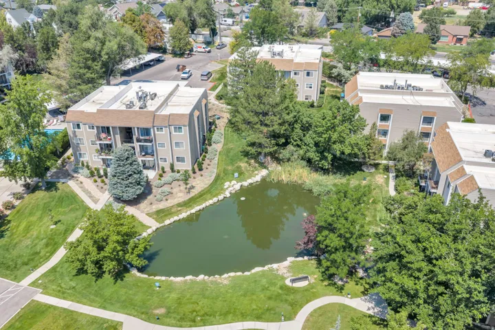 Manicured grounds with a water feature, paved walking paths, and mature trees