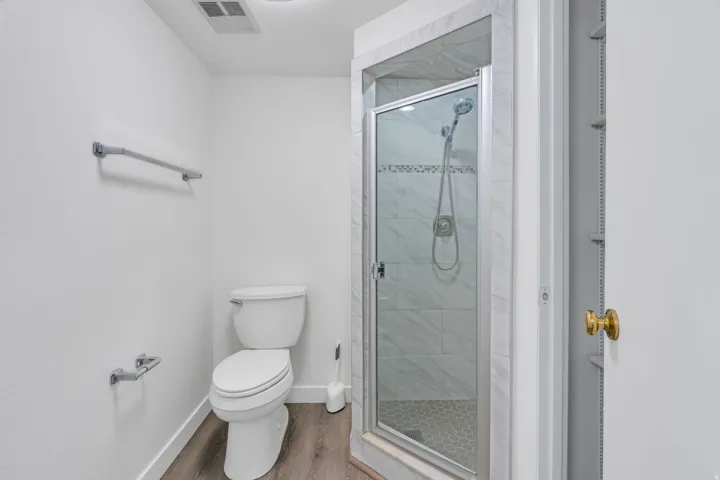 Enclosed shower with glass door, tile surround, and hexagon-patterned floor