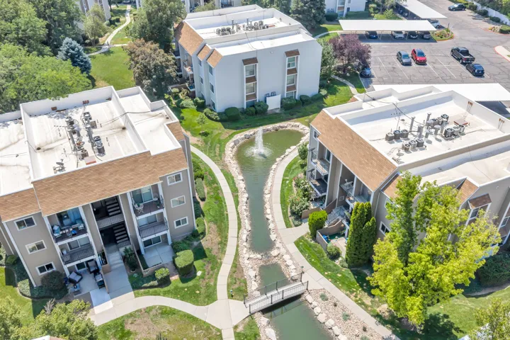 Landscaped grounds featuring a winding water feature with a fountain, pedestrian bridge, and paved pathways