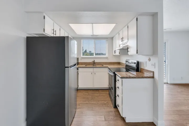 Kitchen featuring white cabinetry, granite-finish countertops, wood-finish flooring, and a stainless steel range