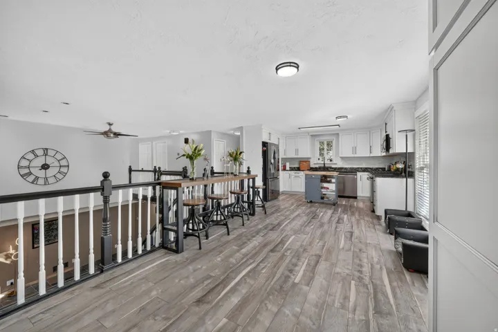 Open-concept upper level with wood-finish flooring, white cabinetry, dark countertops, and stainless steel appliances