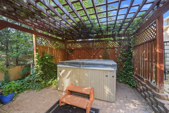 Private outdoor space featuring a hot tub, wood pergola, lattice fencing, and a paver patio