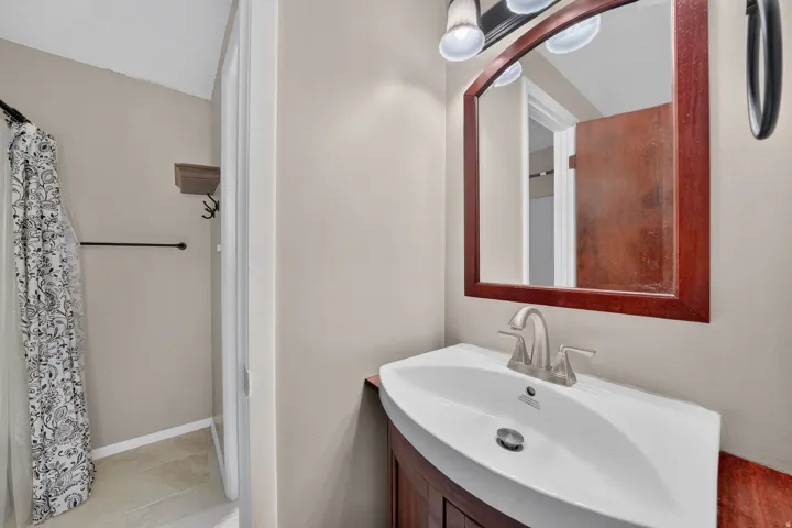 Bathroom featuring a white vanity sink, a wood-framed mirror, a brushed nickel faucet, and neutral wall paint