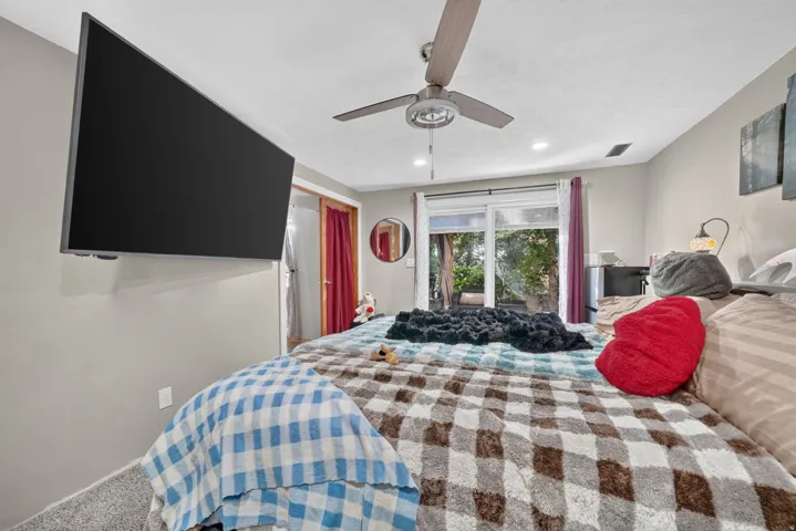 Ceiling fan with integrated lighting, wall-mounted display, sliding glass doors, and light-toned wall paint