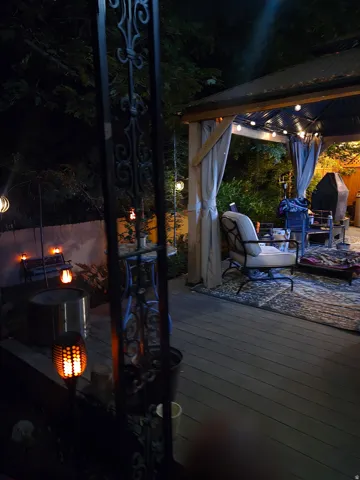 Outdoor deck with a covered gazebo, built-in fire pit, and privacy curtains