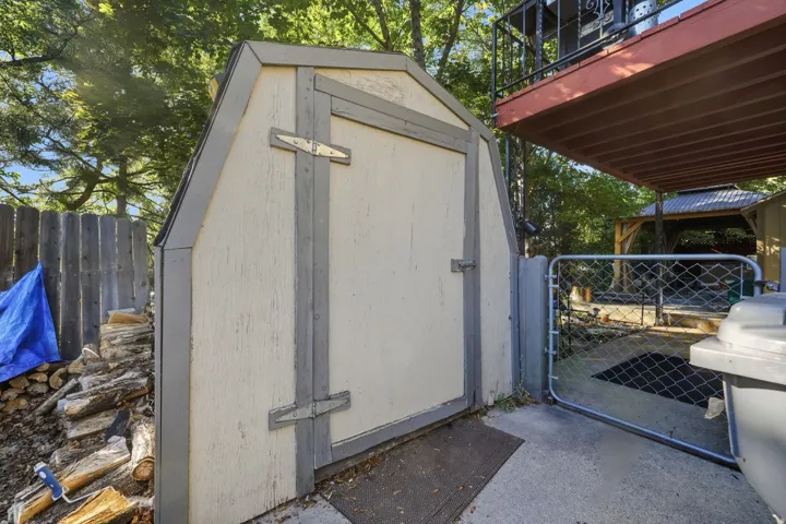 Utility shed with a gabled roof and a wooden fence
