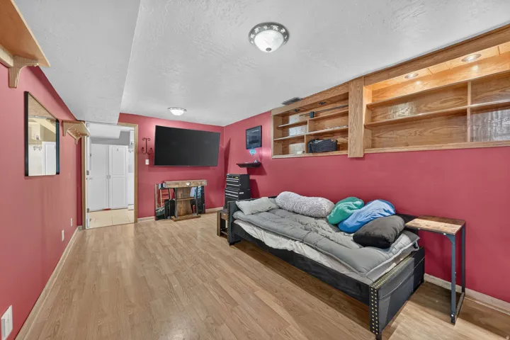 Wood-finish flooring throughout, integrated ceiling lighting, and built-in wood shelving with integrated lighting