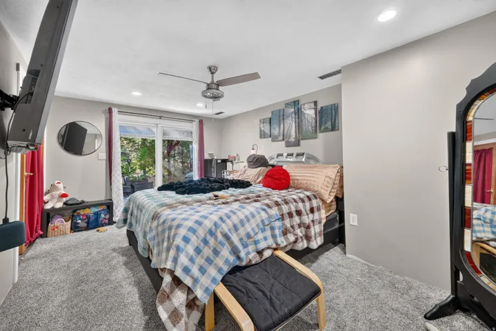 Plush gray carpeting, sliding glass door, recessed lighting, and a ceiling fan