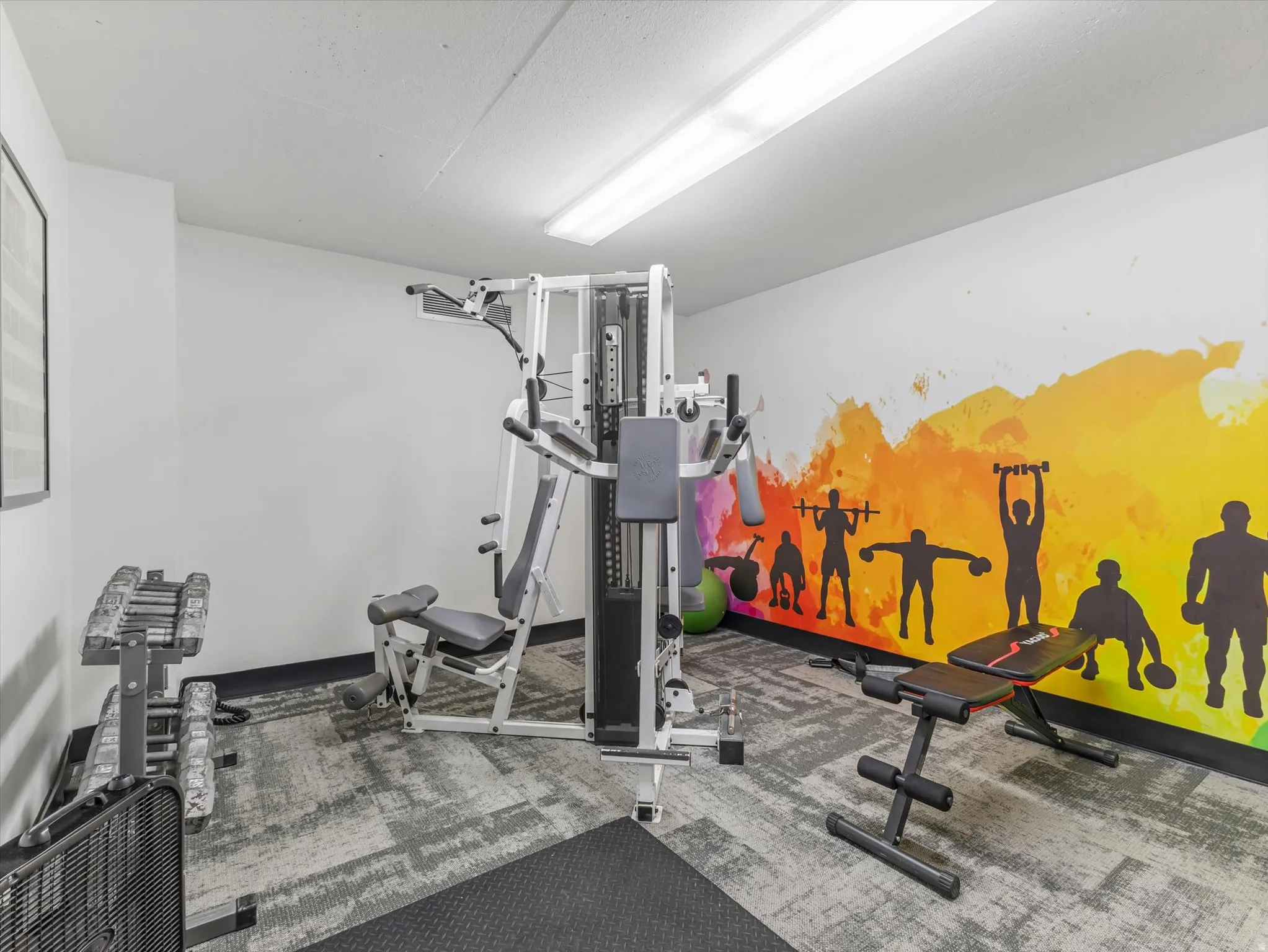 Dedicated fitness area with specialized flooring and bright wall mural