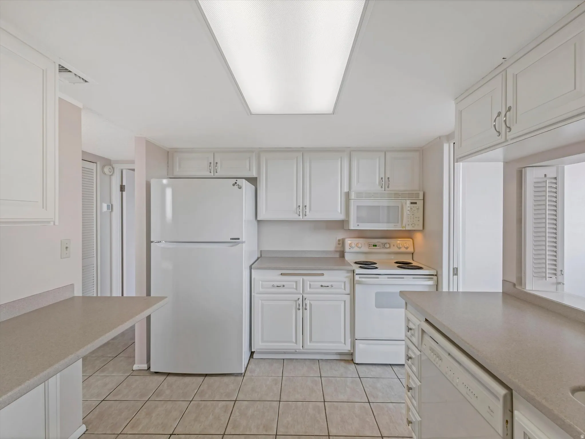Kitchen featuring white cabinetry, integrated appliances, solid surface countertops, a full-size refrigerator, and tile flooring
