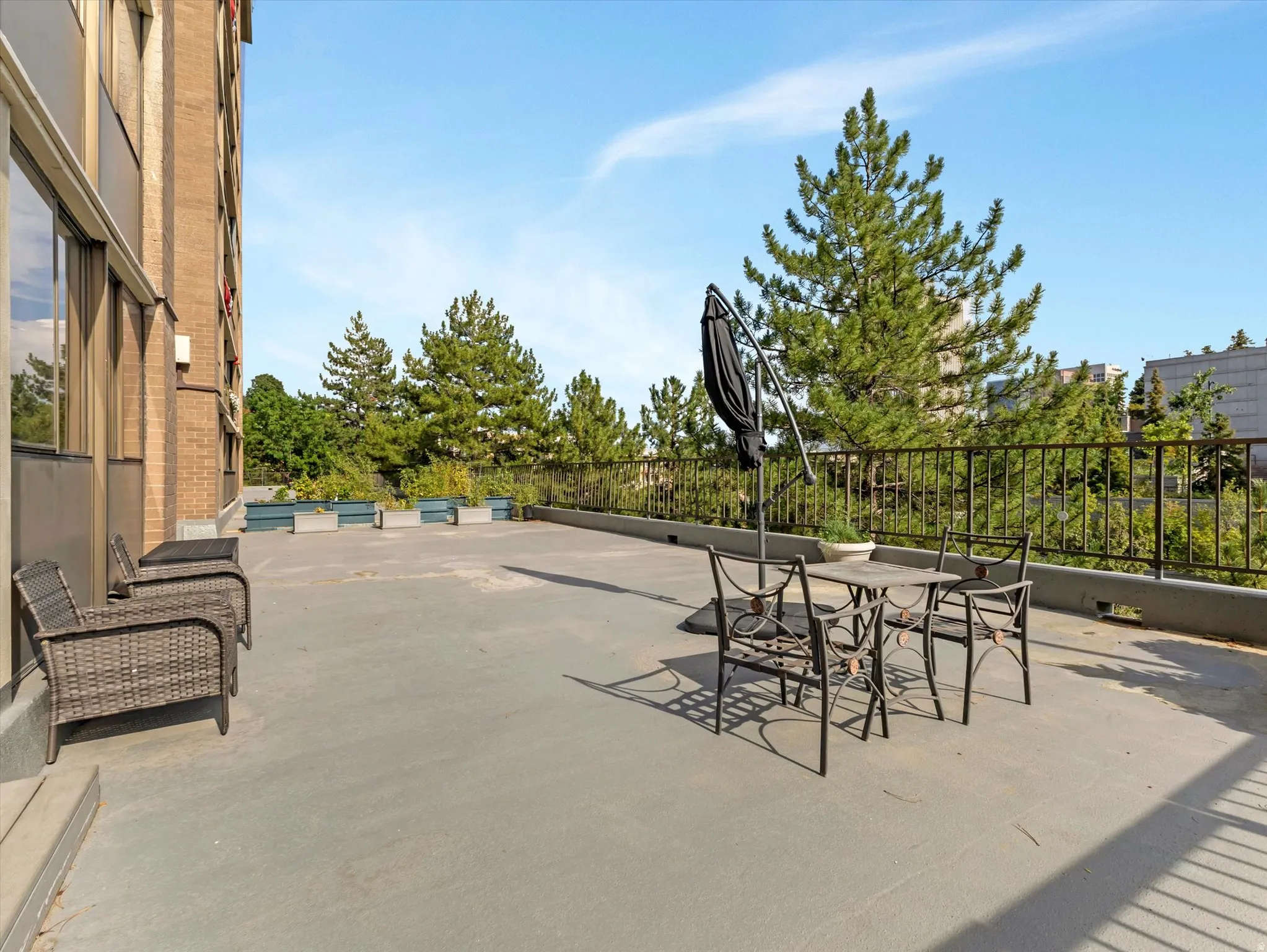 Expansive outdoor patio with concrete surfacing, metal railings, and integrated planters