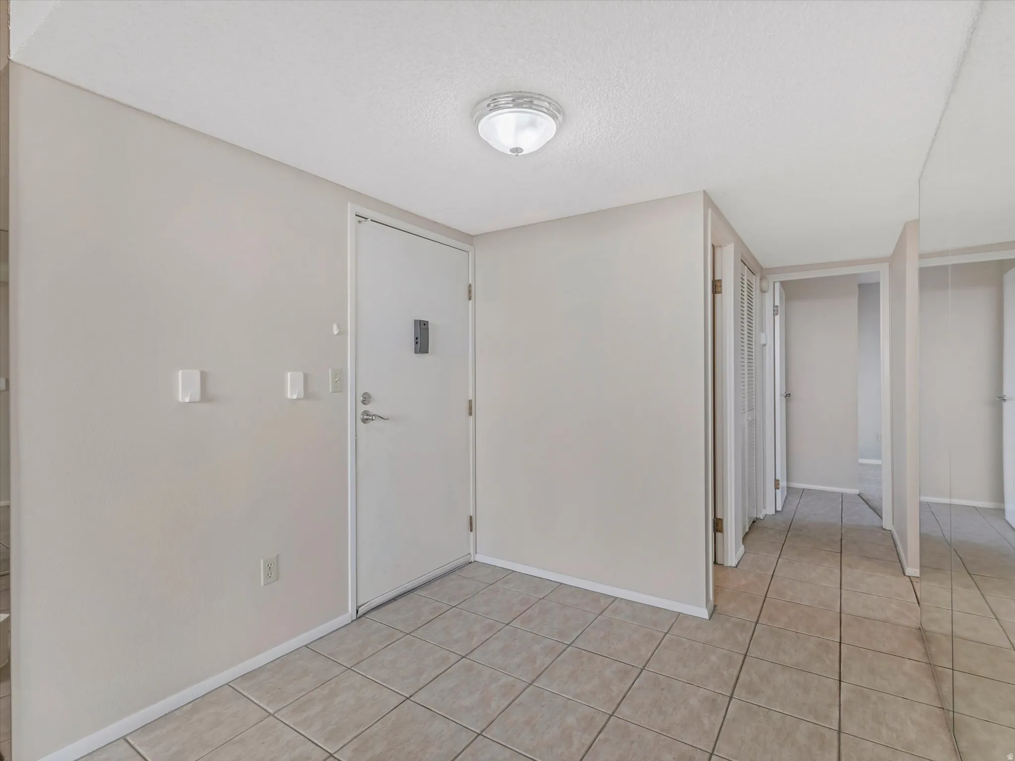 Tile flooring throughout, with a flush-mount ceiling light fixture, and a white interior door with hardware