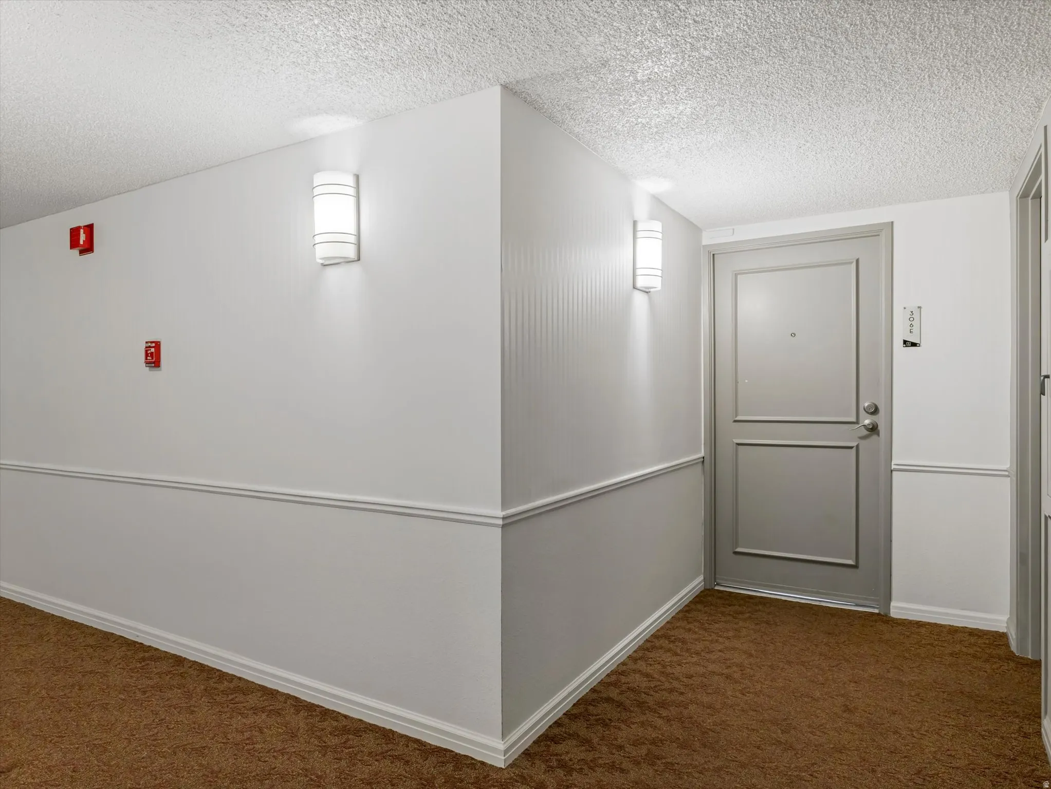 Entryway featuring a paneled door, wall sconces, and brown carpeting