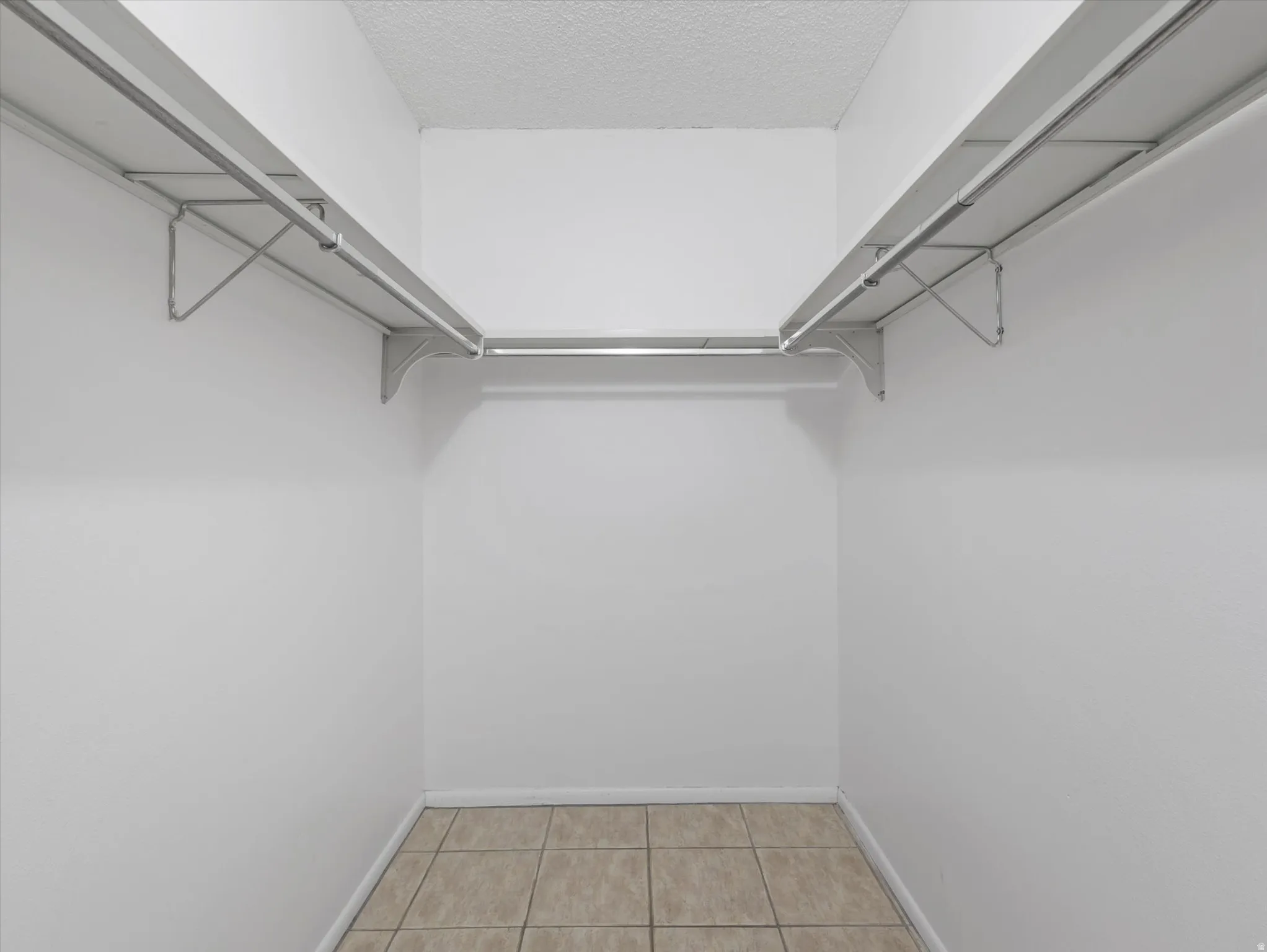Tile flooring, white walls, built-in shelving, and metal hanging rods