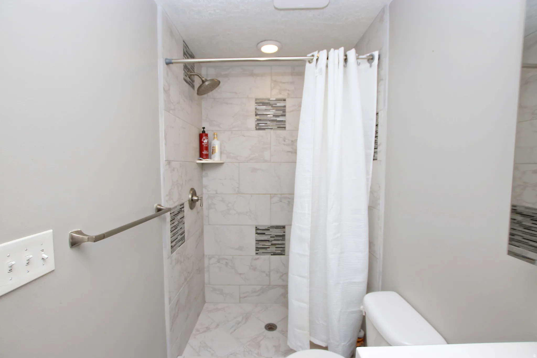 Private ensuite bathroom with updated tile enclosure and floor.