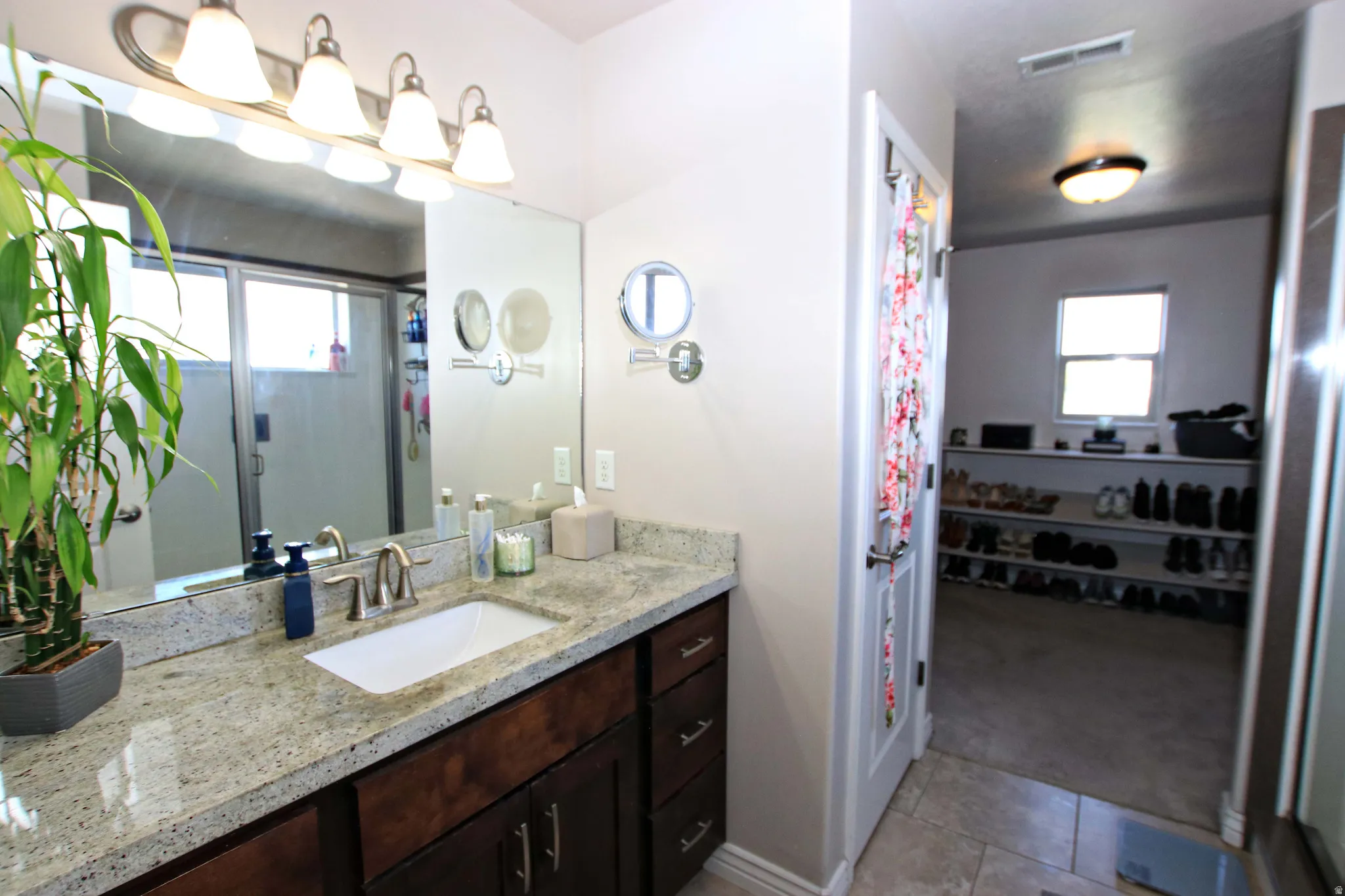 Master bathroom featuring vanity with wood cabinetry, granite countertop, and polished nickel fixtures as well as a double shower with two shower heads.