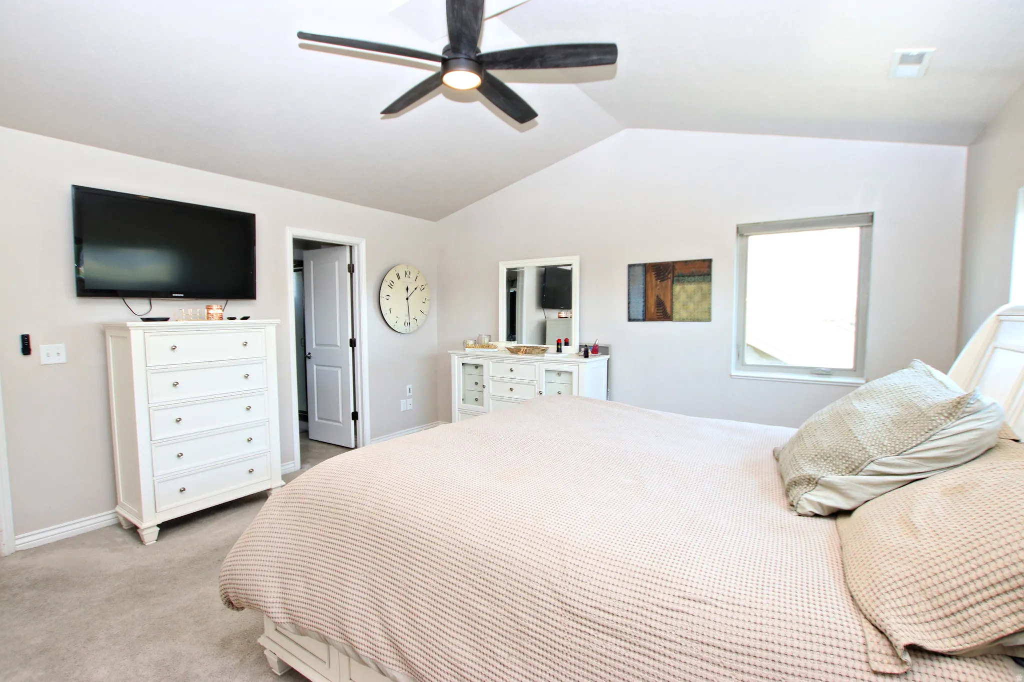 Vaulted ceiling with an attached ceiling fan, carpeted flooring, and a single window