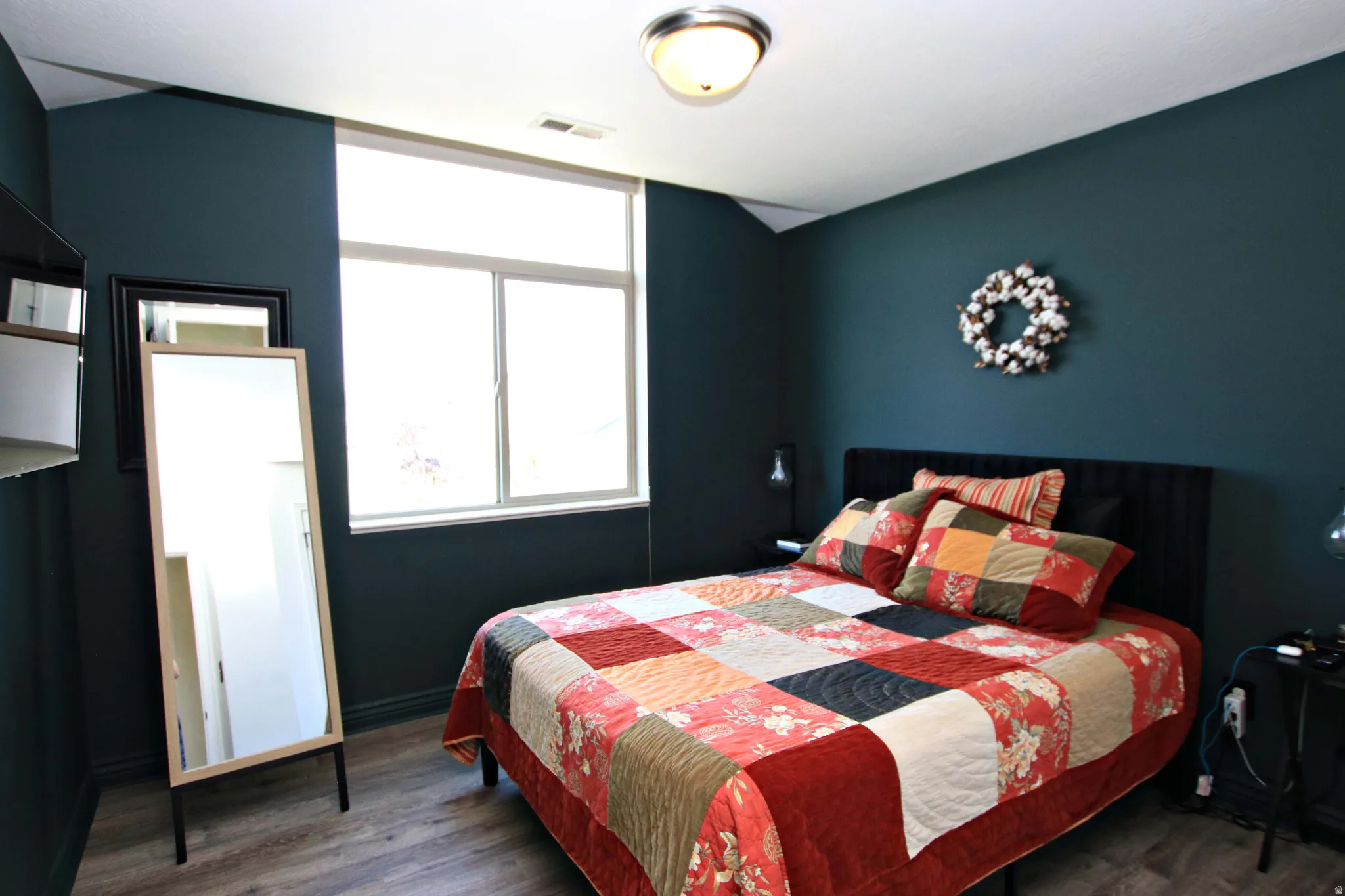 Wood-finish flooring, a contemporary ceiling light fixture, and a large window
