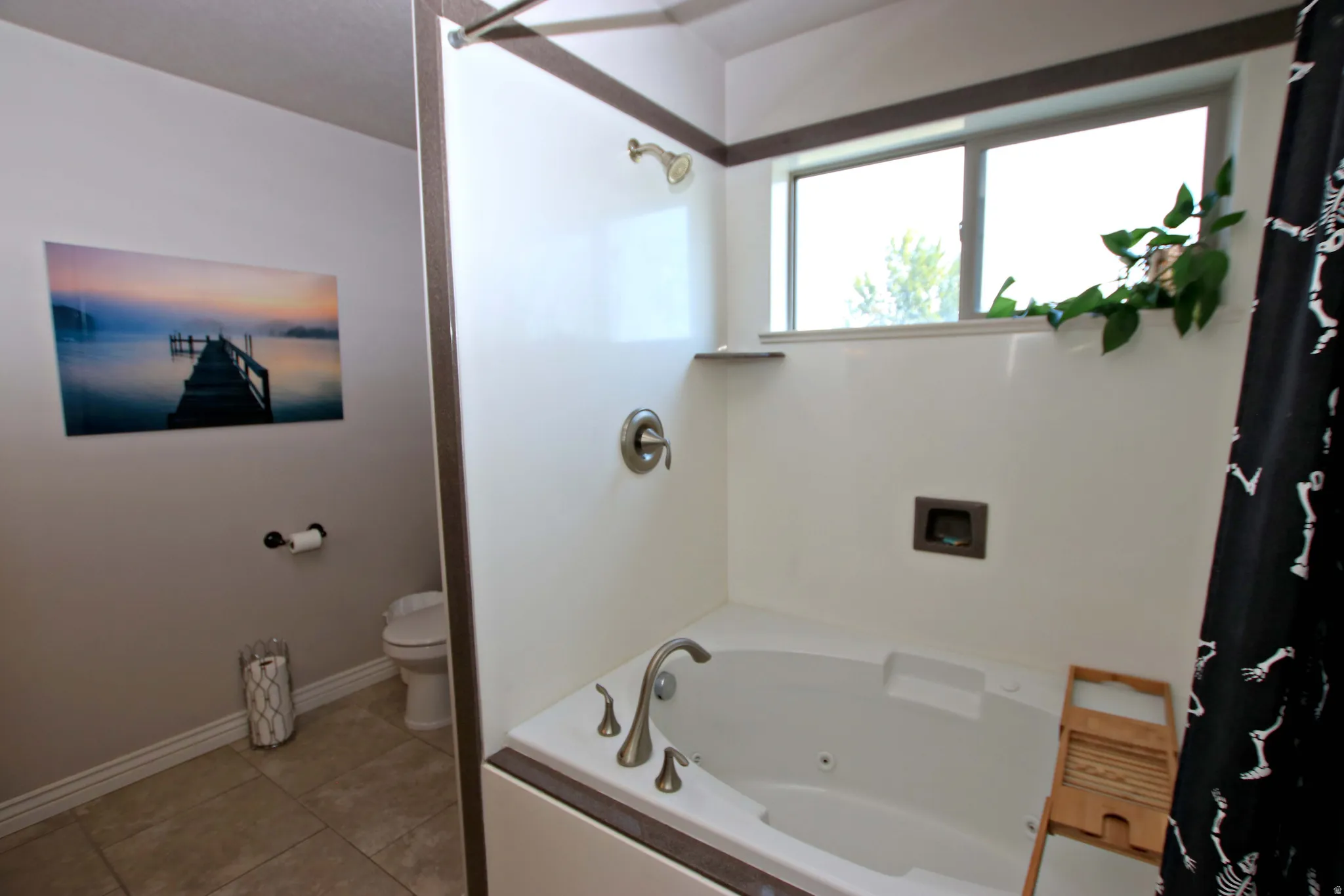 Jetted soaking tub with a brushed nickel faucet, an integrated shower, and a large window