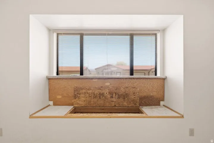 Built-in window alcove featuring a window with horizontal blinds and a base constructed from wood paneling