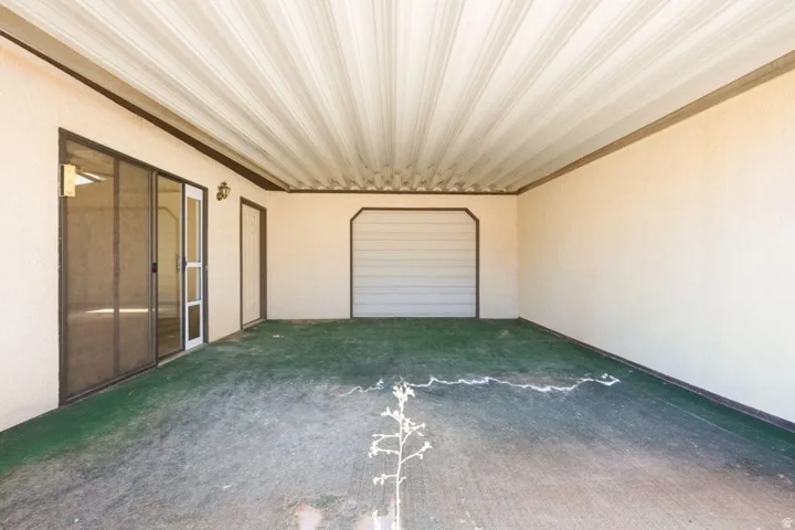 Covered patio area featuring a corrugated ceiling, stucco walls, and an exterior light fixture