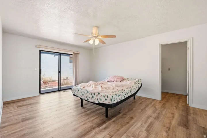 Wood-finish flooring, white walls, ceiling fan, sliding glass door, and a built-in door frame