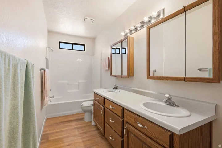 Dual vanity with wood-finish cabinetry, integrated sinks, and individual mirrored medicine cabinets