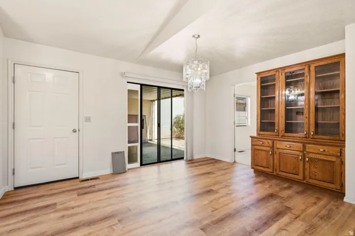 Wood-finish flooring, built-in wooden cabinetry with glass-front uppers, sliding glass doors, and a decorative chandelier