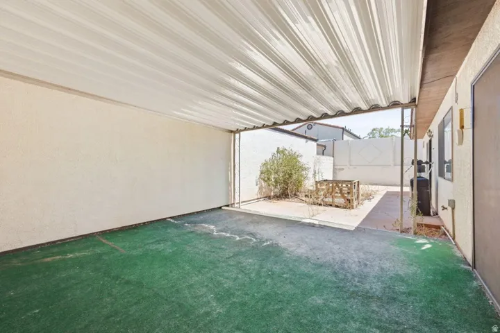 Covered patio with retractable shade system and artificial turf flooring, opening to a secondary outdoor entertaining space