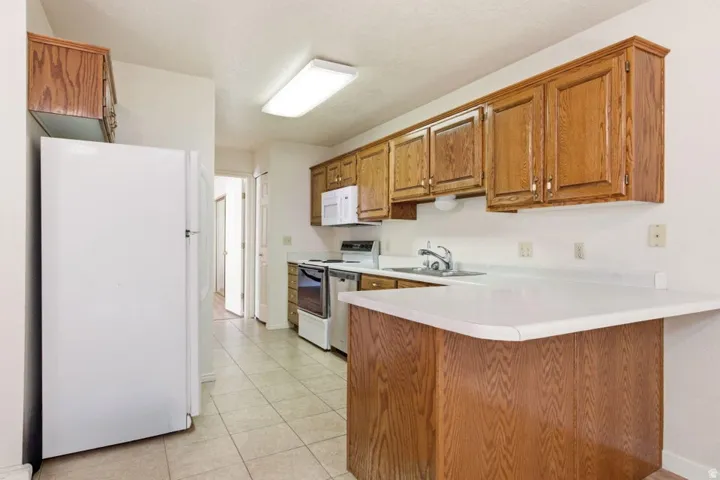 Kitchen featuring wood cabinetry, white countertops, a stainless steel sink, and tile flooring