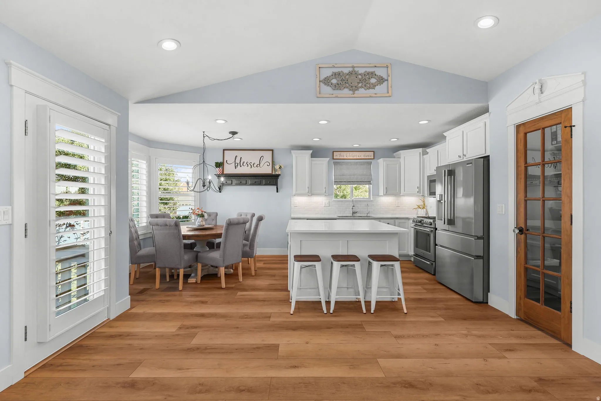 Vaulted ceiling above a kitchen with white cabinetry and stainless steel appliances