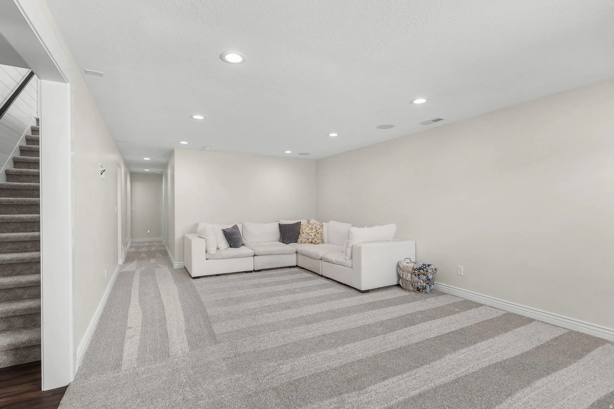 Recessed lighting, light-toned walls, and striped carpeting
