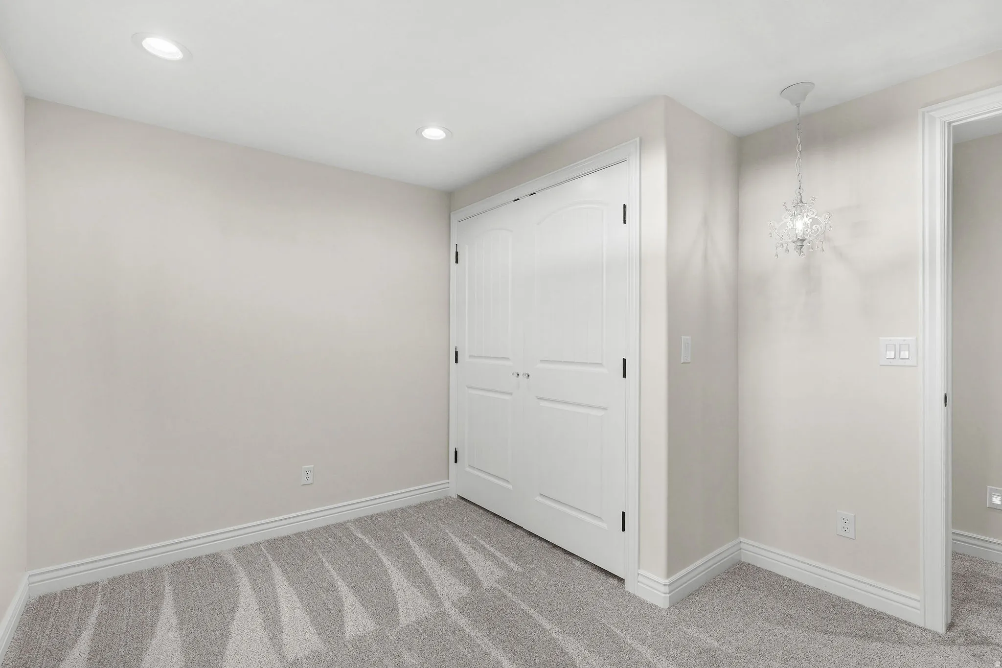 Recessed lighting, arched closet doors, crown molding, patterned carpeting, and a decorative ceiling fixture