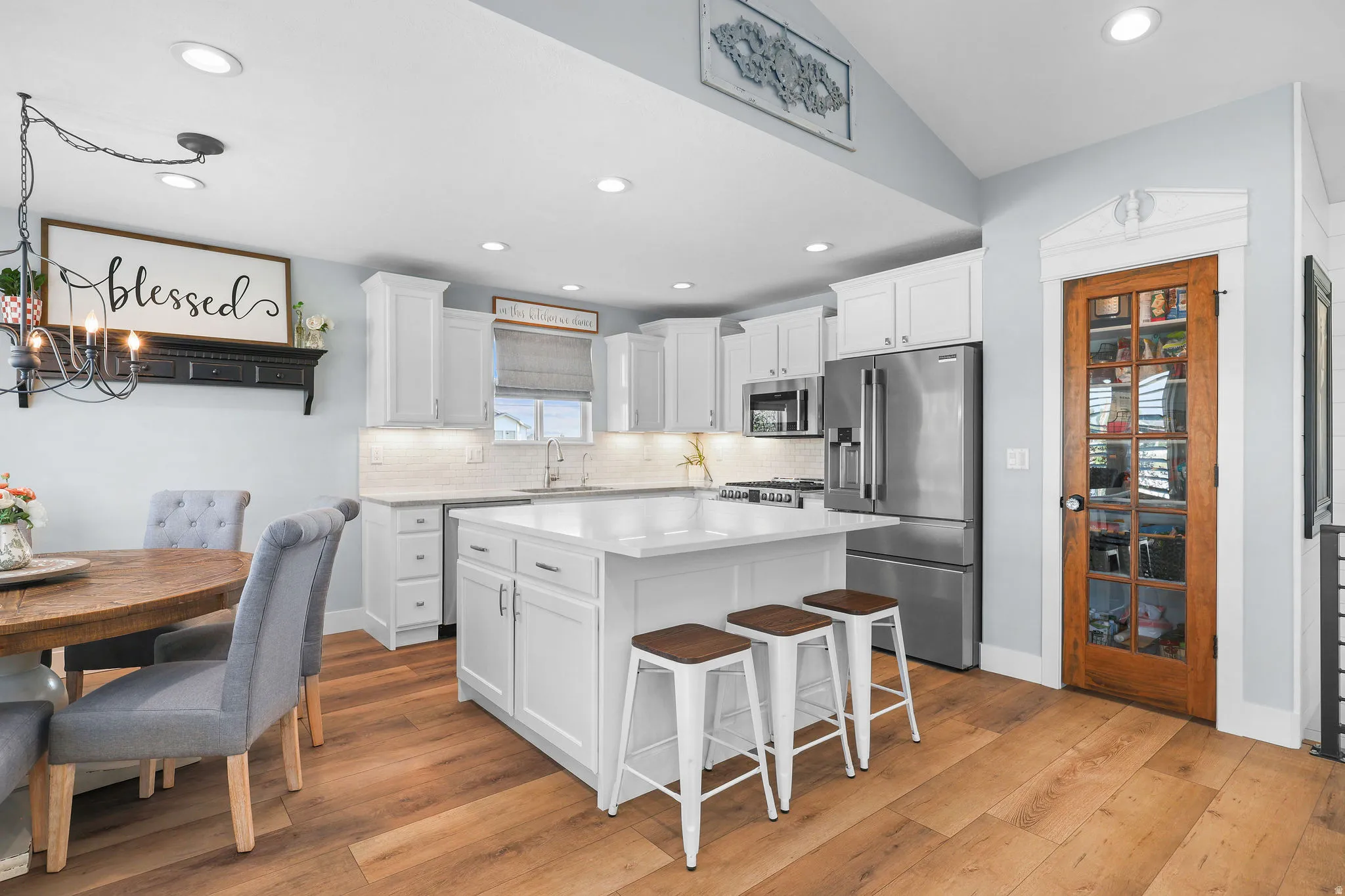 White cabinetry, stainless steel appliances, and wood-finish flooring