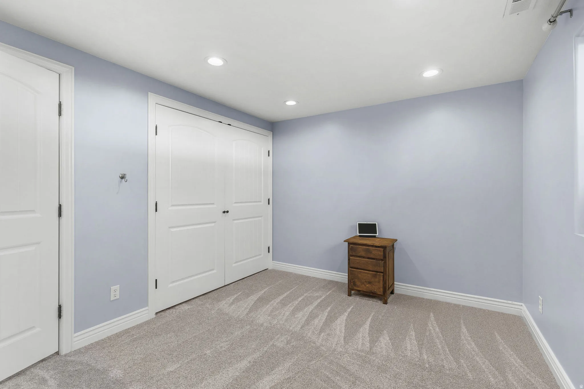 Recessed lighting, light-toned walls, and neutral carpeting