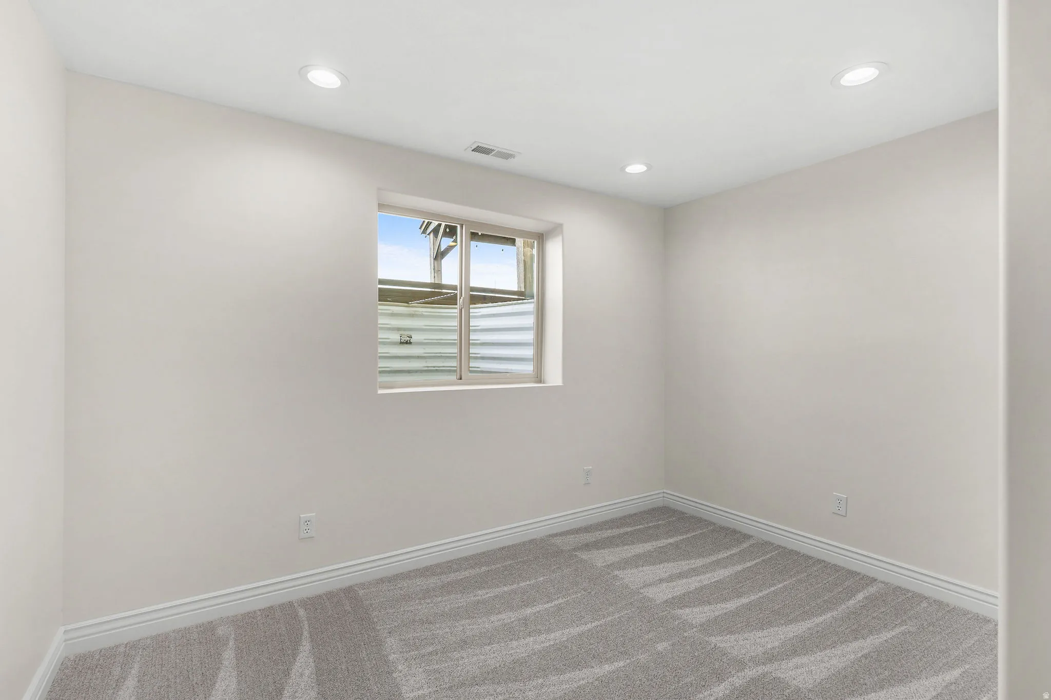 Recessed lighting, light gray walls, window, and patterned carpeting