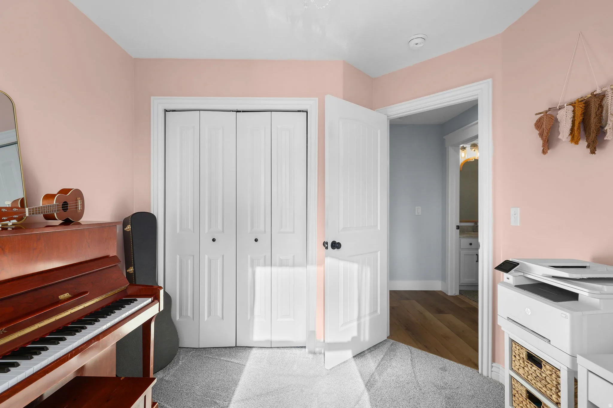 White bi-fold closet doors, white interior door with black hardware, and light pink wall paint