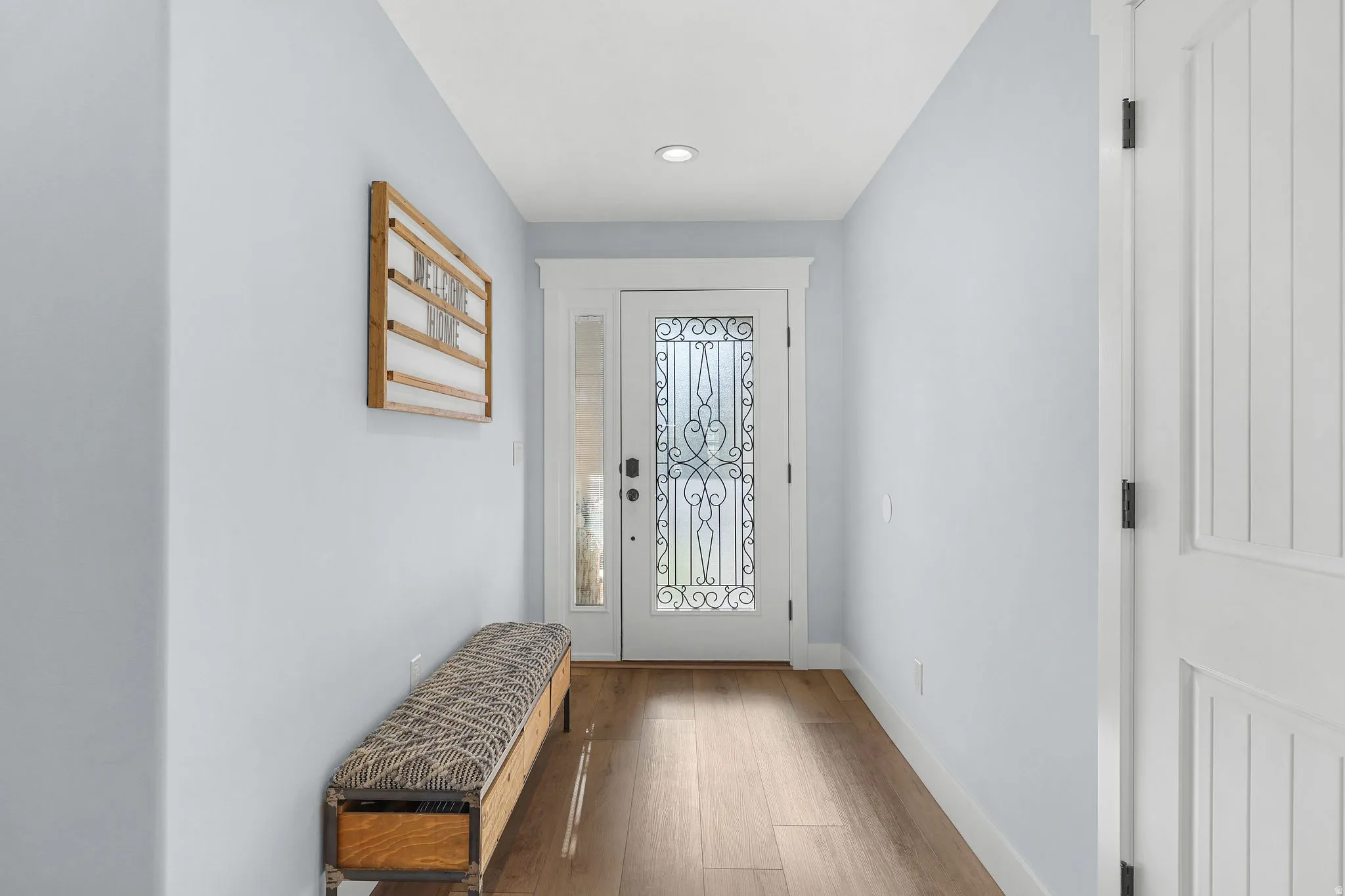 Entryway featuring wood-finish flooring, recessed lighting, and a white paneled door
