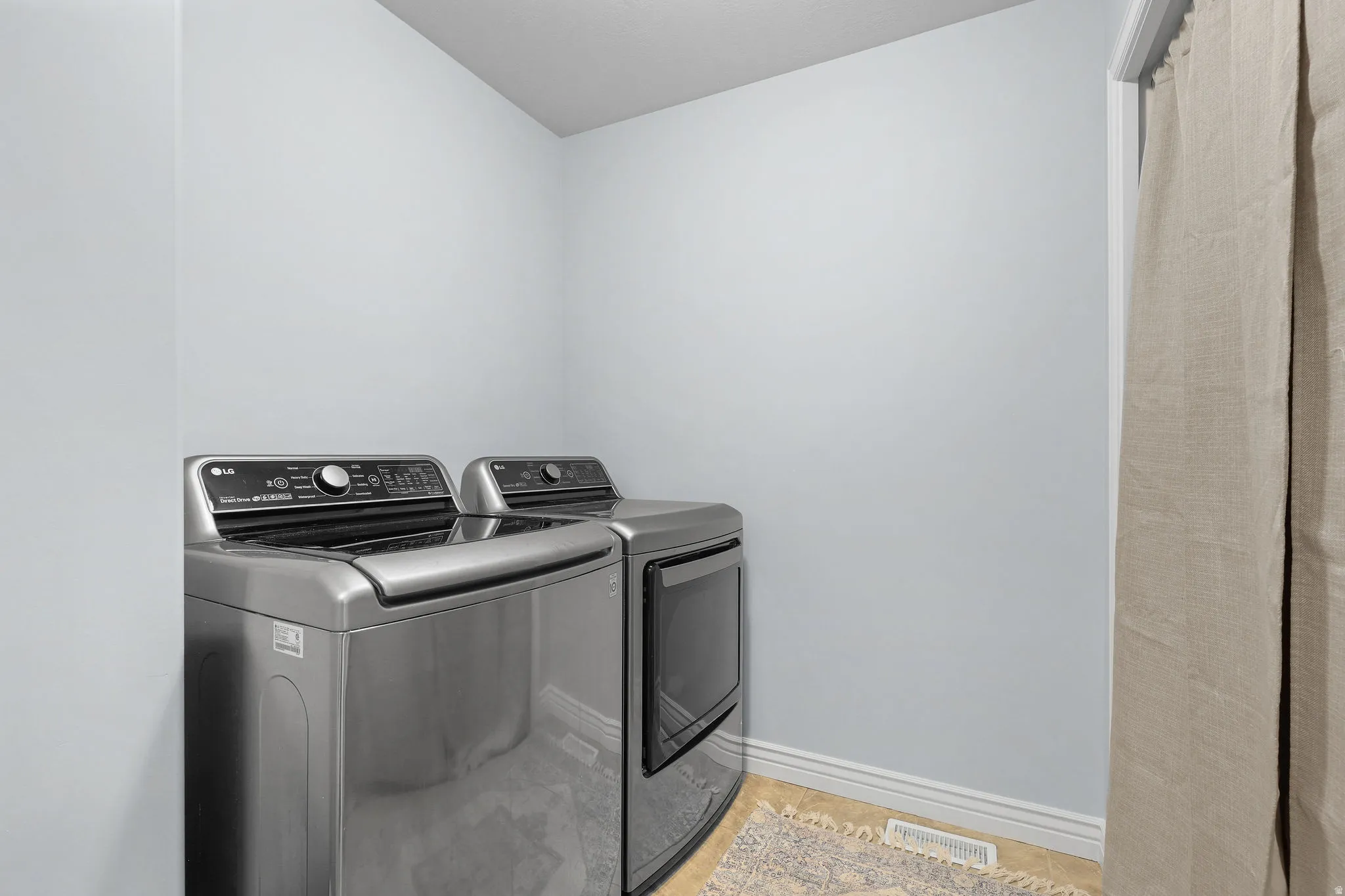 Laundry area with light-colored walls and tile flooring