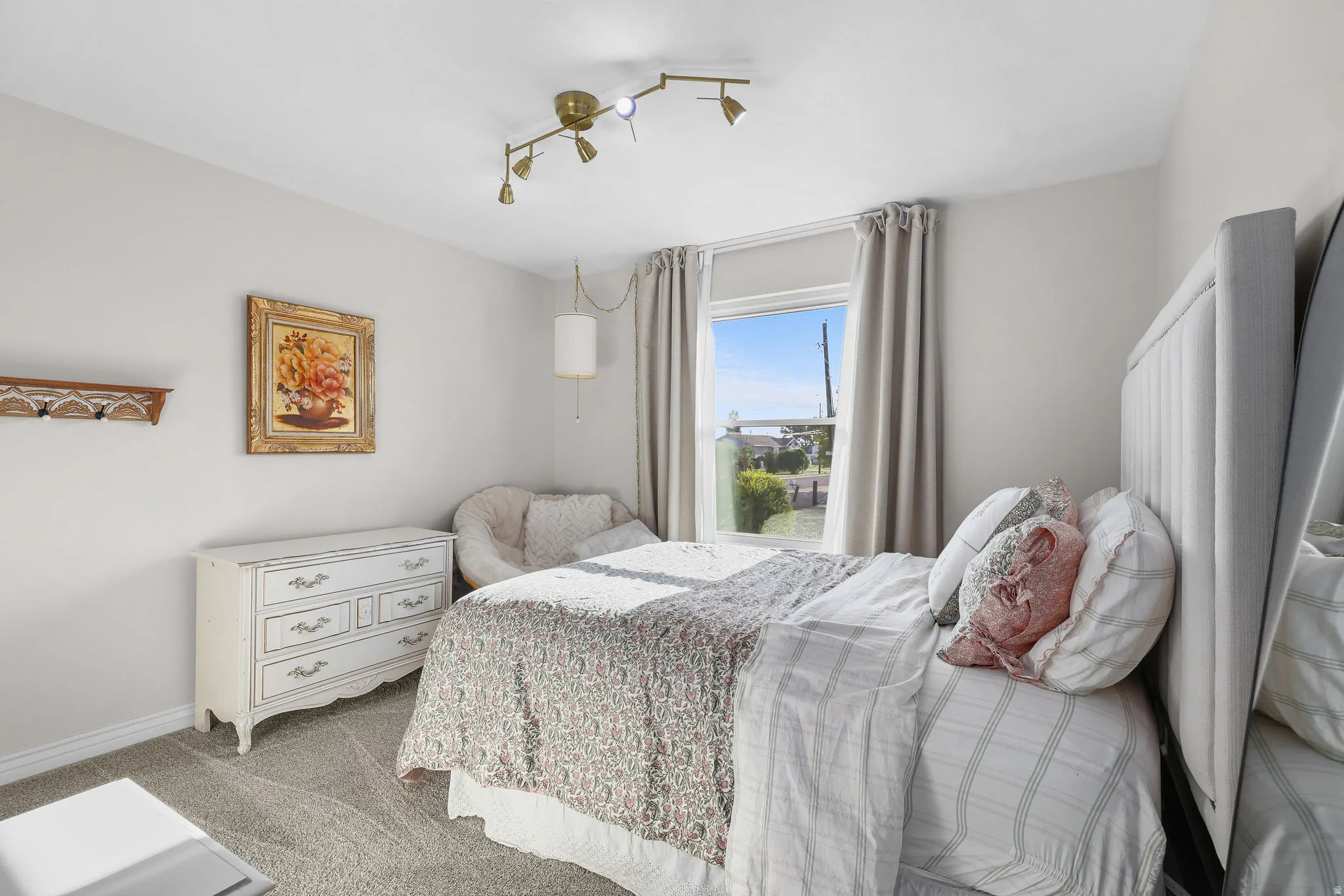 Single window with drapes, wall-mounted track lighting fixture, and carpeted flooring